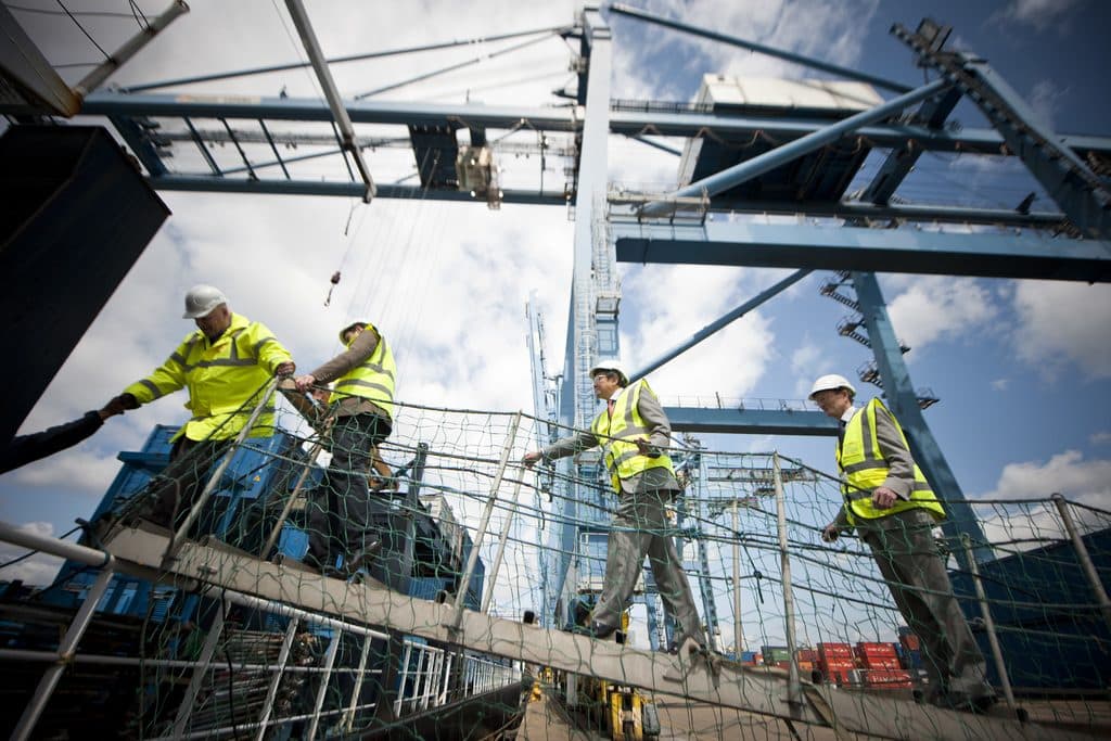 Engineers in hard hats and high-visibility vests working on a steel structure against the sky