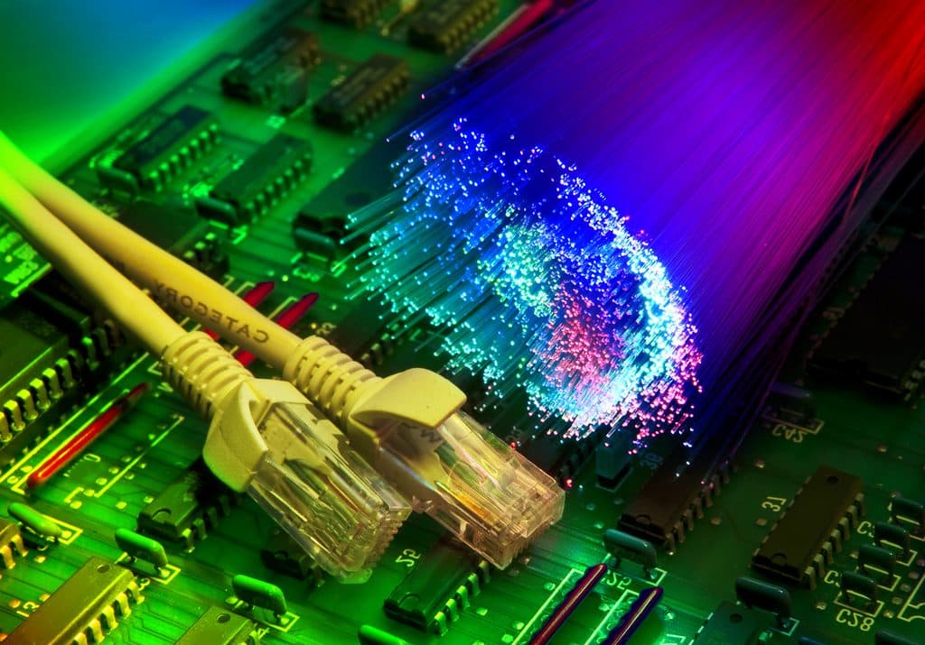 Glowing fibre-optic strands and network cables over a circuit board