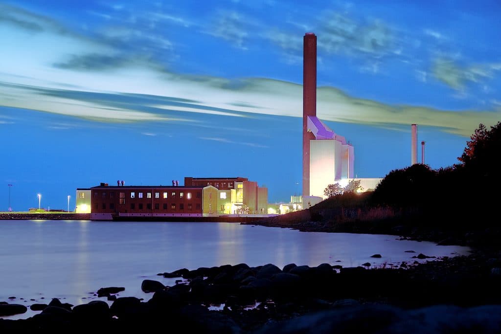 Power plant with a tall chimney on the waterfront at dusk