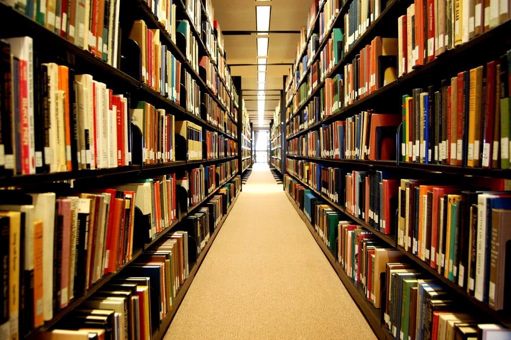 Aisle between tall library shelves filled with books