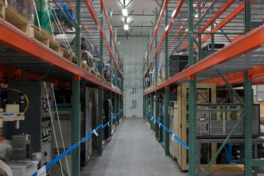 Aisle between tall orange pallet racks in a warehouse