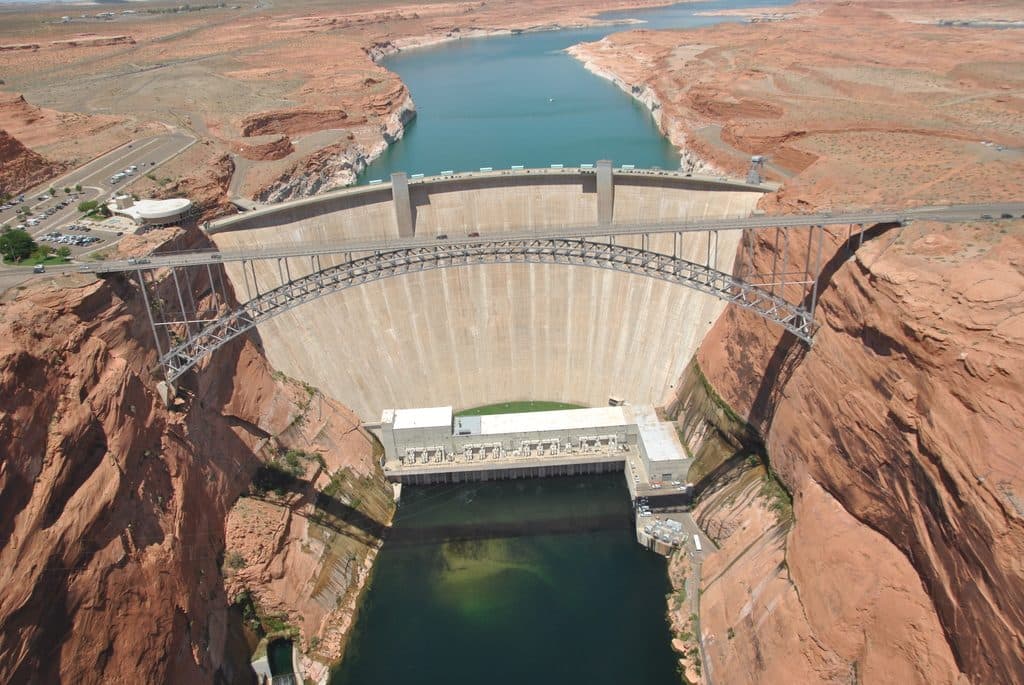 Aerial view of a concrete arch dam and reservoir in a desert canyon