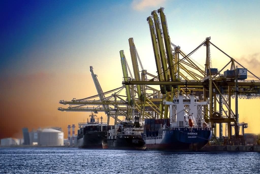 Ship-to-shore cranes over cargo vessels at a port at dusk