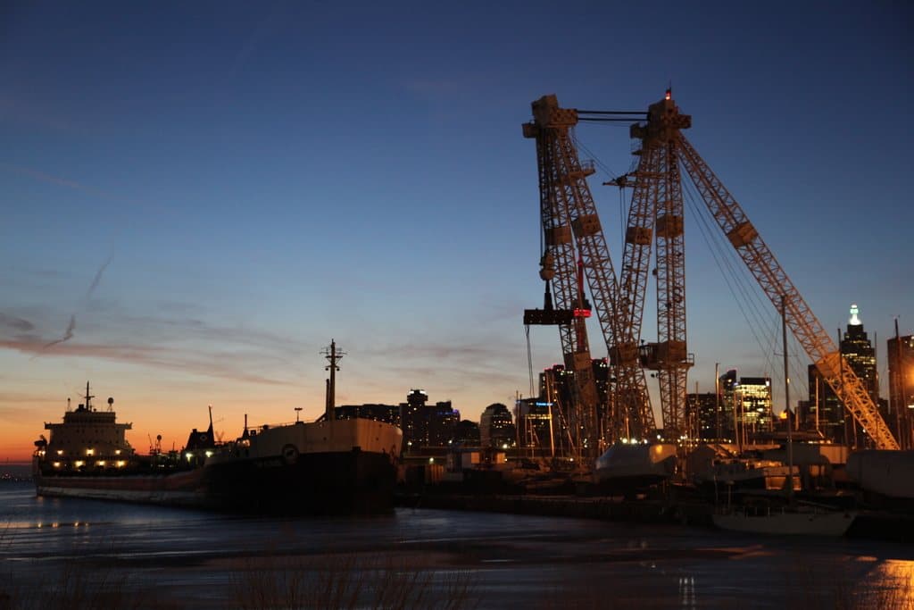 Container port at dusk with gantry cranes and a city skyline